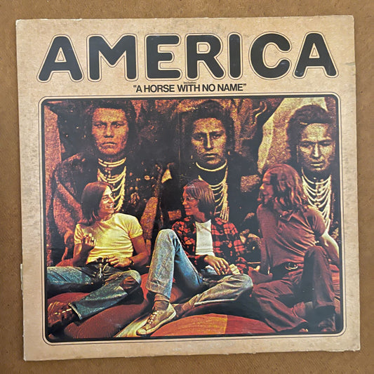 America cover art for vinyl record album has an native America Navaho sitting as though he’s unhappy, dressed in ceremonial dress